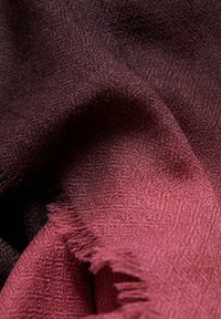 Tela suave y tejida que presenta un degradado desde un burdeos profundo hasta un rosa pálido, con bordes deshilachados y sutiles variaciones de textura.
