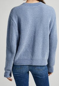 Suéter azul de punto con textura acanalada, mangas anchas y escote redondeado. El dobladillo y los puños son acanalados para un acabado ajustado.