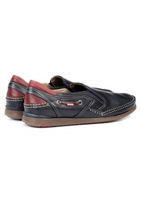 Zwarte leren instapschoenen met een rode leren accent, zichtbare stiksels, ronde neus en een stevige bruine zool.