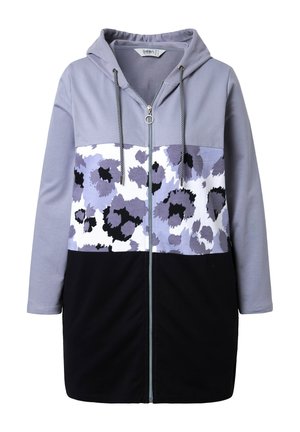Veste à capuche zippée avec un design en blocs de couleurs, comprenant des sections gris clair, lavande et noir, rehaussées d'un imprimé léopard en violet et noir.