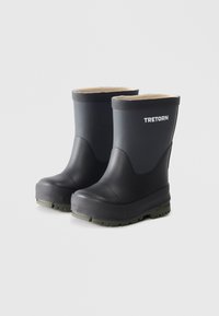 Botas de lluvia de goma negras con una superficie texturizada, forro interior suave y suela verde. Logo "TRETORN" en la parte frontal.