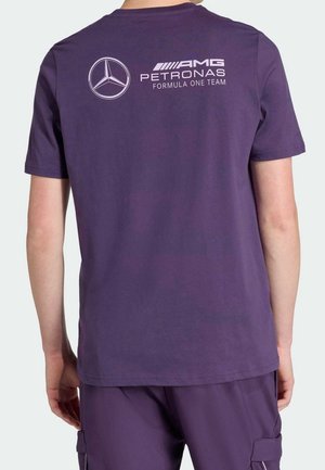 Person trägt lila AMG Petronas Formula-One-Team T-Shirt und passende Shorts, von hinten gezeigt.