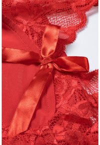 Red lace lingerie with satin ribbon accents, featuring intricate lace patterns and a smooth texture, highlighting a delicate design.