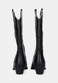 Botas de tobillo negras con punteras en punta, patrones florales en relieve y un tacón grueso. Hechas de cuero suave con detalles de costura en contraste.
