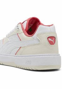 Biele kožené tenisky s ružovými akcentmi, štruktúrovaná podrážka a logo Puma na päte. Obsahujú polstrovaný golier a šnúrky.