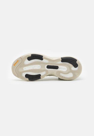 Shoe sole featuring a textured pattern with grooves, black rubber accents, and light-colored cushioning, designed for grip and support.