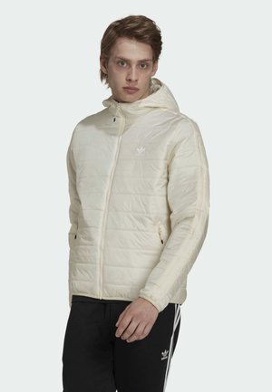 Giubbotto imbottito color crema con design trapuntato, chiusura con zip, tasche laterali e cappuccio. Presenta strisce a contrasto lungo le maniche e il logo.