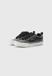 Black and grey suede sneakers with a low profile, round toe, black laces, white rubber sole, and side logo detail.