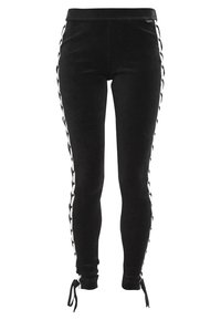 Svarta mocka leggings med vita flätade sidopaneler, med en figurnära passform och justerbara snören vid vristerna för en anpassningsbar passform.