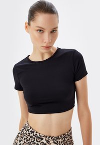 Sort cropped T-shirt lavet af glat, strækbart stof. Har en rund halsudskæring og korte ærmer, ideel til lagdeling eller afslappet brug.