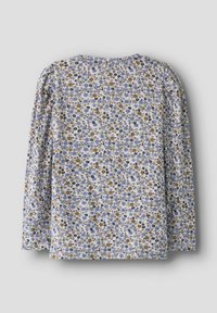 Overhemd met lange mouwen met een kleine bloemmotief in blauw, bruin en zwart op een witte achtergrond, plat uitgestald op een grijze ondergrond.