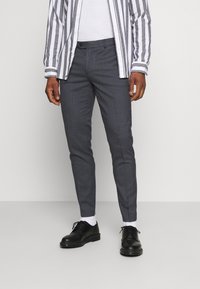 Grå stribede bukser med slim fit, der har flad front, sidelommer og manchetter, parret med sorte snøresko og hvide sokker.