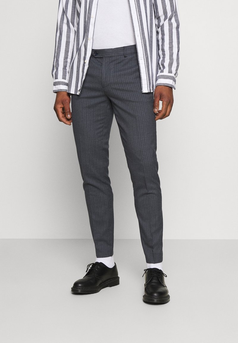 Grå stribede bukser med slim fit, der har flad front, sidelommer og manchetter, parret med sorte snøresko og hvide sokker.