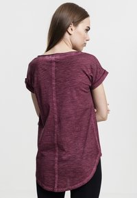 Bordo īsām piedurknēm krekls ar noapaļotu apakšu, neapstrādātām malām un smalku tekstūru. Aizmugures skatā redzama vaļīga piegriezuma forma un pievērstās piedurknes.