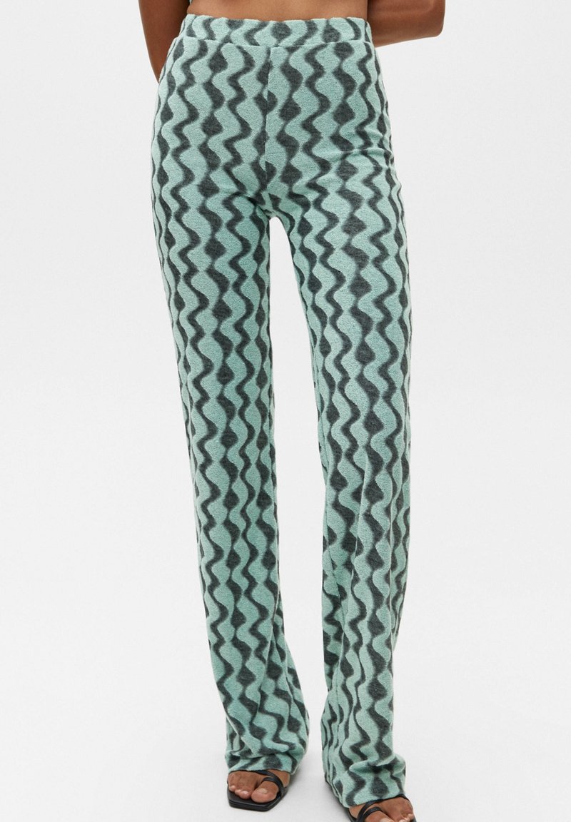 Light blue patterned pants with a wavy dark gray design. They are fitted at the waist, with a flared leg and soft, textured fabric.