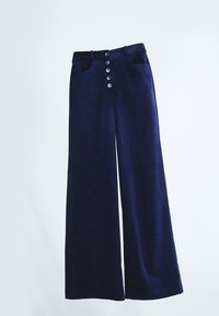 Pantalons en velours côtelé bleu marine à jambes larges avec taille haute, fermeture par bouton sur le devant et deux poches avant, présentés sur un fond blanc.