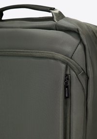 Sac de voyage texturé vert foncé avec une poignée supérieure et une poche zippée à l'avant. Dispose d'un tissu durable et d'un design épuré.