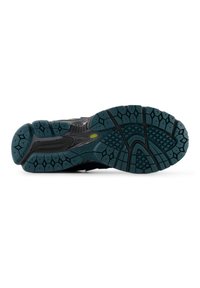 Μαύρη σόλα αθλητικού παπουτσιού με υφή πράσινης λαβής, που διαθέτει εξαγωνικά σχέδια, αυλακώσεις ευελιξίας και εμφανές λογότυπο κατασκευαστή.