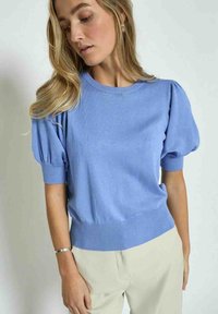 Hele sinine kudumissviiter lühikeste puhvärvidega, soonikute äärtega ja soonikuga alumise äärega. Pehme tekstuur, vaba lõige ja ümar kaelus.