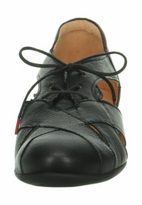 Chaussure en cuir noir avec un bout rond, un design découpé et un système de laçage. Texture lisse avec une semelle flexible et des accents minimaux.