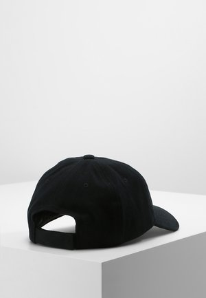 Sort justerbar baseballkasket placeret på en hvid kube, vist bagfra med en buet skygge og stofrem.