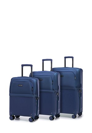 Three navy blue suitcases in graduated sizes, featuring a smooth top section and textured ribbed bottom, all with retractable handles and spinner wheels.