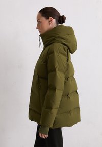 Olijfgroene pufferjack met capuchon, met een rits aan de voorkant en elastische manchetten; gewatteerde textuur met verborgen zakken.