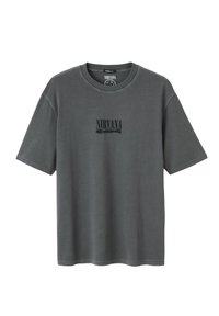 T-shirt en coton gris avec un col rond, des manches courtes et le logo "NIRVANA" imprimé en noir sur le devant. Coupe décontractée et texture douce.