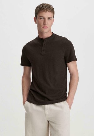 Bruin korte mouwen henley-shirt met een drieknoopsluiting, gemaakt van zachte stof. Gepaard met lichtgekleurde, ontspannen pasvorm broek.