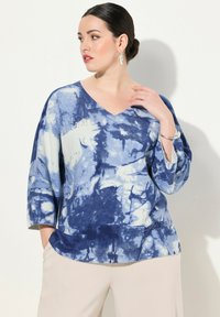 Maglione a maglia tie-dye blu e bianco con scollatura a V, maniche a tre quarti e motivo testurizzato. Presenta dettagli decorativi lungo lo scollo.