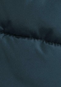 Tessuto imbottito blu scuro con una texture liscia, caratterizzato da cuciture e una superficie leggermente lucida, che indica un materiale isolante.