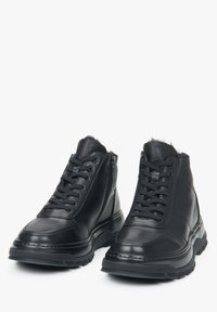 Zwarte hoge leren schoenen met een gestructureerd oppervlak, vetersluiting en een rubberen zool met een lichte plateau.