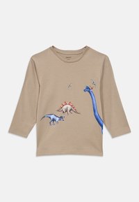 Μπεζ μακρυμάνικο παιδικό πουκάμισο με πολύχρωμα σχέδια δεινοσαύρων και ιπτάμενου πτερόδακτυλου στο μπροστινό μέρος.