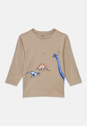 Béžna otroška majica z dolgimi rokavi, na sprednji strani s pisanimi potiski dinozavra in letečega pterodaktila.