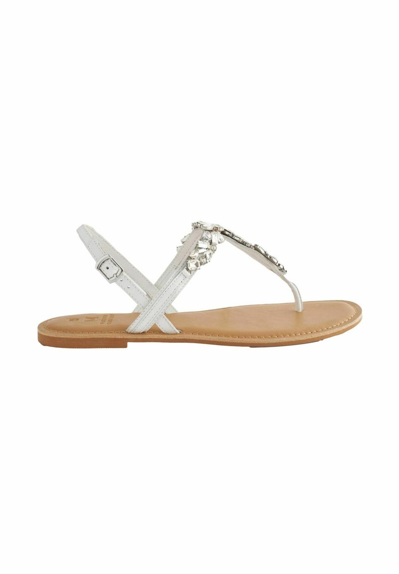 Sandali piatti bianchi con design a infradito, dotati di perline decorative, cinturino alla caviglia regolabile e un soletta liscia color tan.