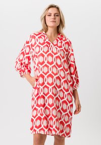 Rood en wit gestreepte jurk met een V-hals, driekwart mouwen en zijzakken. Gemaakt van een lichte, gladde stof.