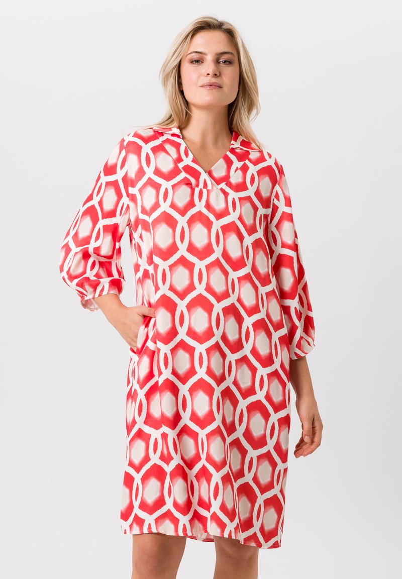 Rood en wit gestreepte jurk met een V-hals, driekwart mouwen en zijzakken. Gemaakt van een lichte, gladde stof.