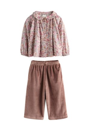 Bluse mit Blumenmuster, in hellpink, mit langen Ärmeln und Kragen, kombiniert mit braunen Cordhosen in knie-langer Länge mit elastischem Bund.