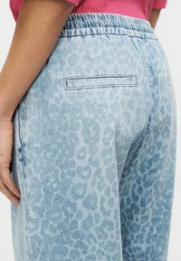Ανοιχτό μπλε παντελόνι τζιν με σχέδιο λεοπάρ, ελαστική μέση και δύο πίσω τσέπες, με άνετη εφαρμογή και μαλακή υφή.