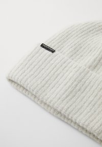 Szary dziany czapka beanie o prążkowanej teksturze. Posiada czarną metkę z napisem "Peak Performance" wyszytym z boku.