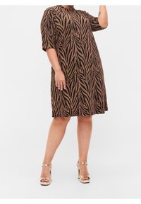 Schwarzes Kleid mit metallic-goldenem Blättermuster, kurzen Ärmeln, runder Halslinie, knielang und getragen mit goldenen High Heels.