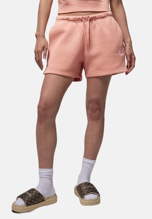 Shorts in cotone rosa con vita elastica e cordoncino; indossati con calze bianche e infradito marroni con motivo e suola a piattaforma.