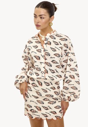 Ensemble chemisier blanc et mini-jupe avec motif coquillage, bords festonnés et accents corail. Confectionné en tissu léger avec manches longues.