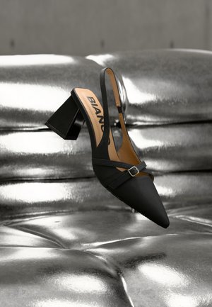 Chaussure à bride arrière noire avec bout pointu et talon bloc large, dotée d'un détail subtil de boucle et d'une texture en tissu doux.