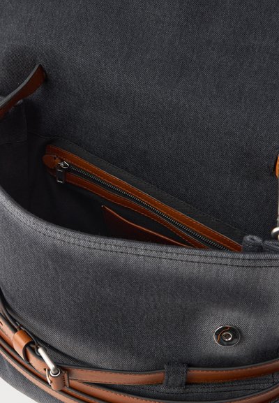 Wnętrze szarej torby materiałowej z brązowymi skórzanymi akcentami i kieszonką na zamek. Posiada bezpieczne zapięcie na zatrzask i gładką teksturę.