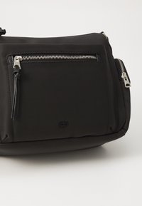 Borsa a tracolla nera in nylon con tasca frontale con zip, hardware in argento e logo in rilievo discreto. Texture morbida, design compatto.