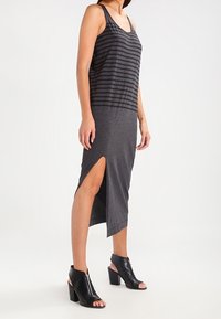 Grårandig ärmlös klänning med en sidoklyfta. Tyget är en mjuk, strukturerad blandning. Kombinerad med svarta öppna tå ankelstövlar med en chunky klack.