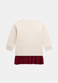 Felpa crema con maniche lunghe e polsini a costine, caratterizzata da una gonna plissettata bordeaux a strati. Texture morbida, design informale e vestibilità rilassata.