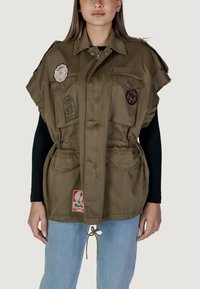 Gilet utility oversize color khaki realizzato in tessuto leggero, caratterizzato da molteplici tasche, toppe con logo e un cordino in vita.