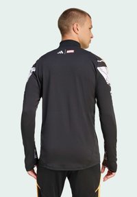 Černá dlouhá rukávová košile s brandingem Marvel, s detailními grafickými potisky na rukávech. Vyrobena z hladké, elastické látky.